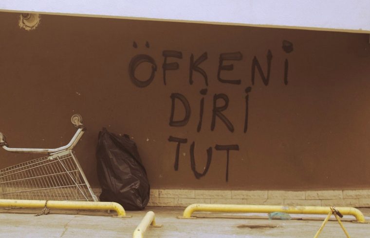 a shopping cart leaning against a wall with graffiti on it