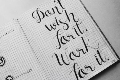Close-up of motivational calligraphy on grid paper, inspiring message for productivity.