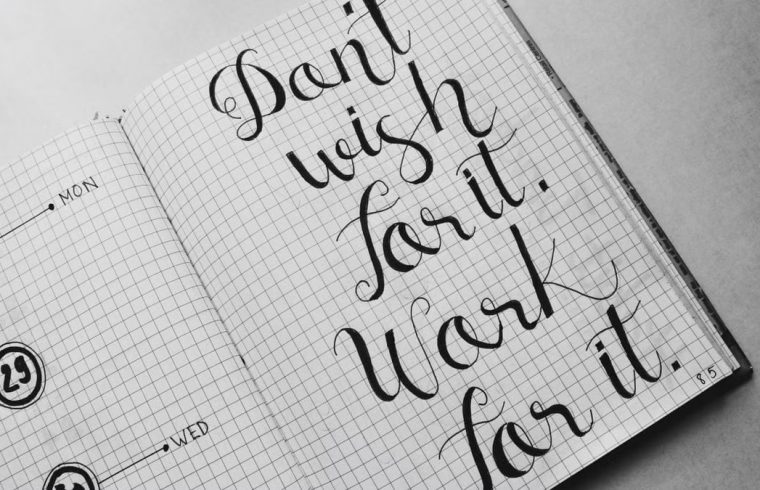 Close-up of motivational calligraphy on grid paper, inspiring message for productivity.